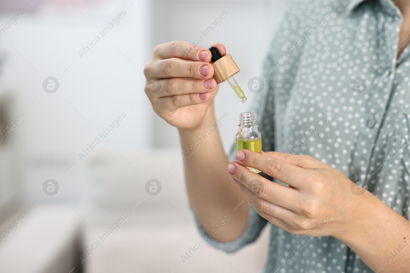 Photo of Young woman taking CBD tincture indoors, closeup. Space for text