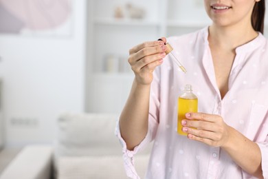 Young woman taking CBD tincture indoors, closeup. Space for text