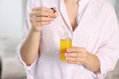 Photo of Young woman taking CBD tincture indoors, closeup