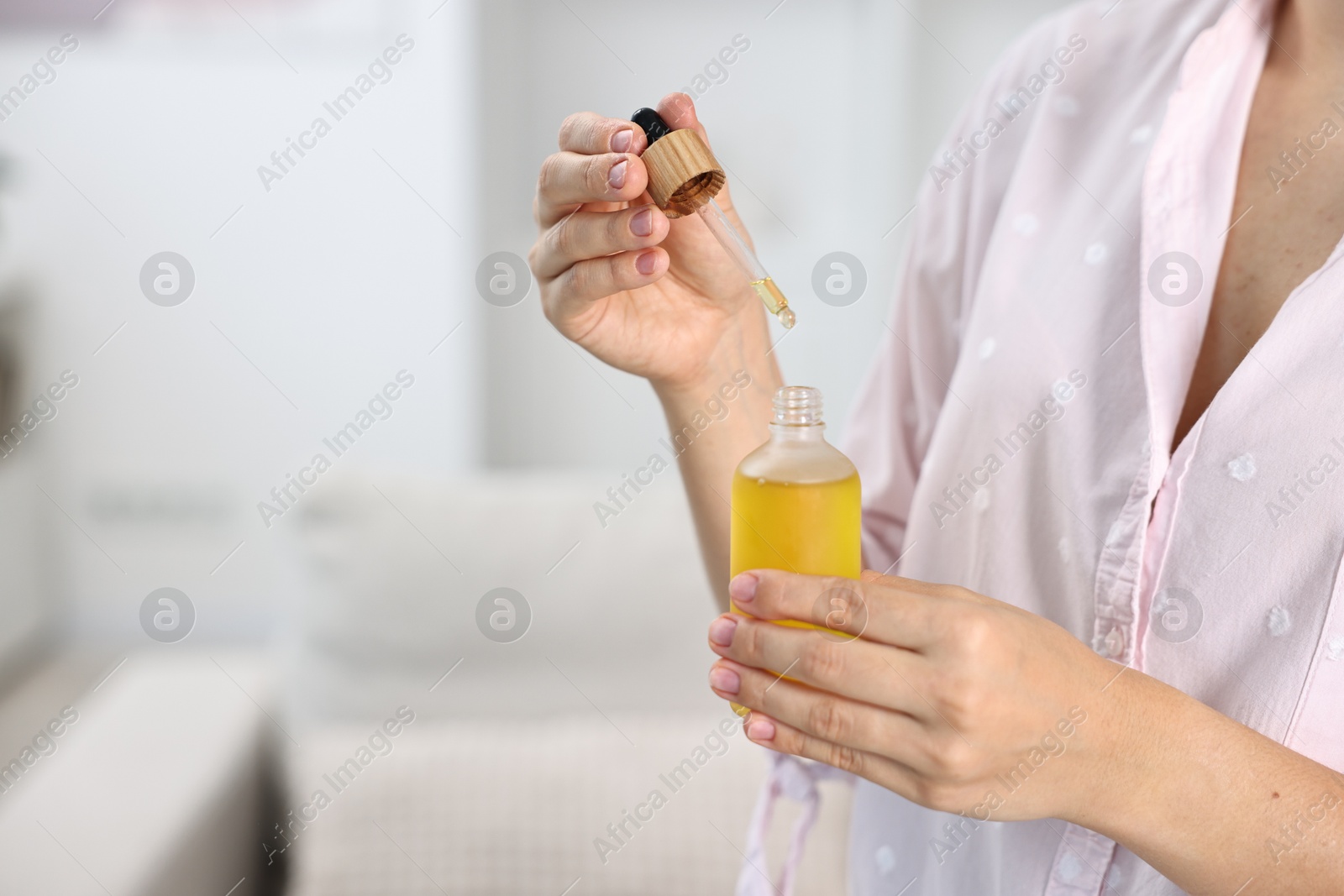 Photo of Young woman taking CBD tincture indoors, closeup. Space for text