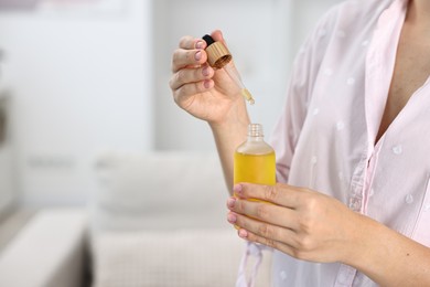 Young woman taking CBD tincture indoors, closeup. Space for text