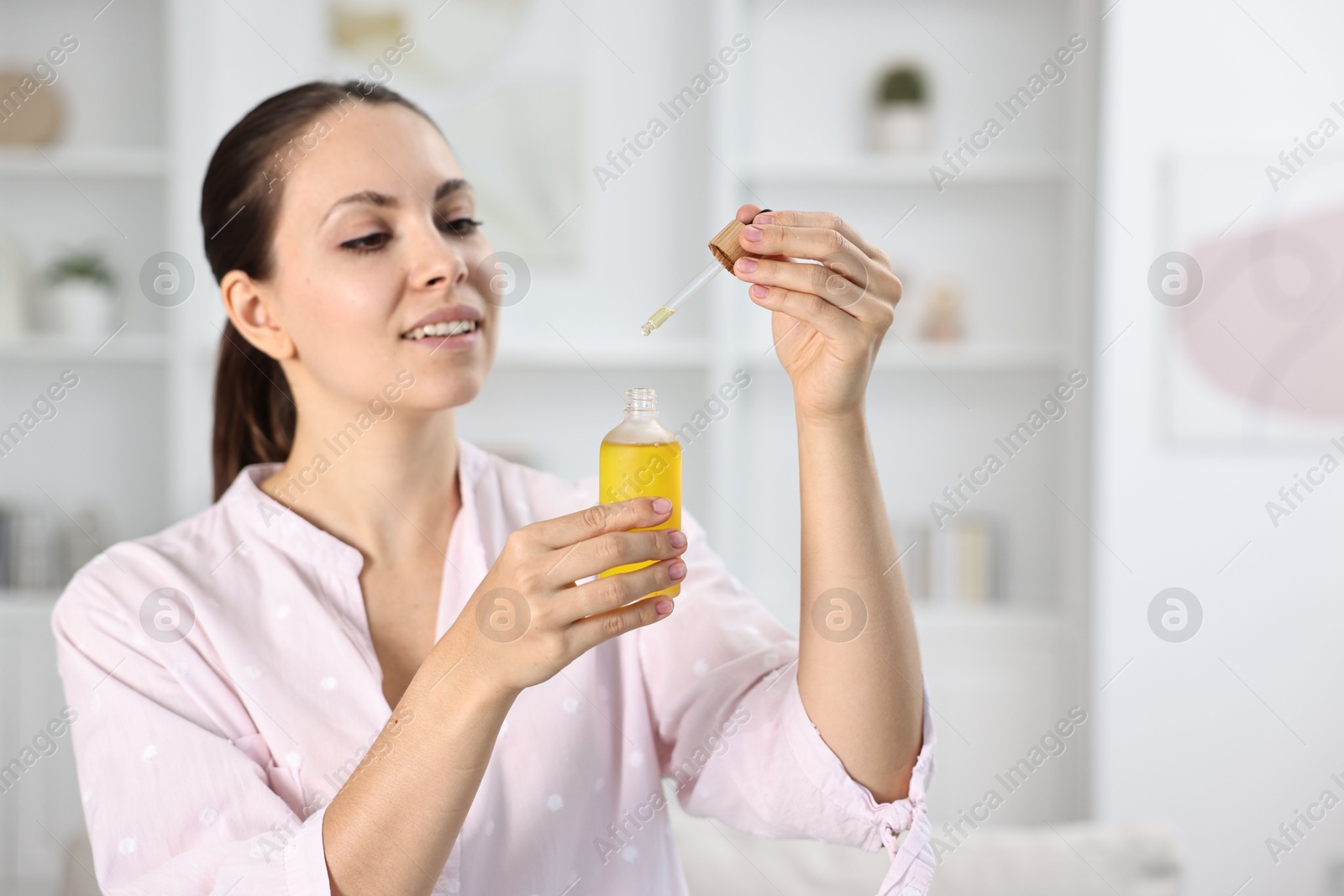 Photo of Young woman taking CBD tincture indoors, space for text