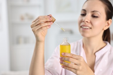 Photo of Young woman taking CBD tincture indoors. Herbal extract