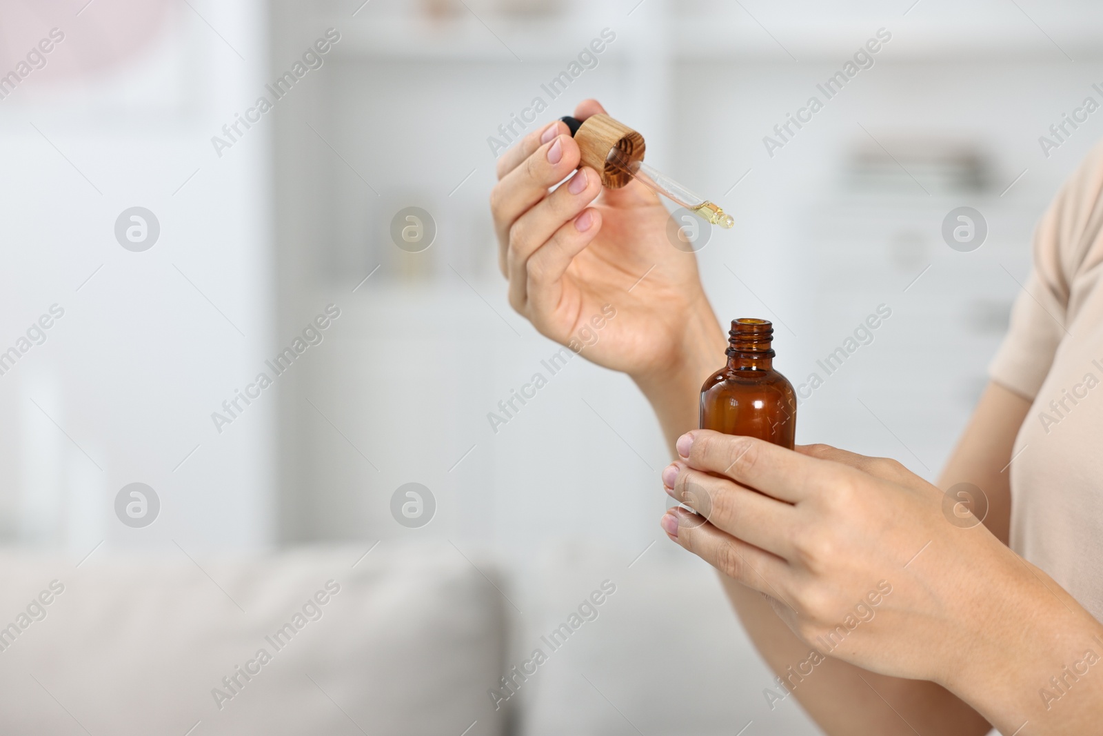 Photo of Young woman taking CBD tincture indoors, closeup. Space for text