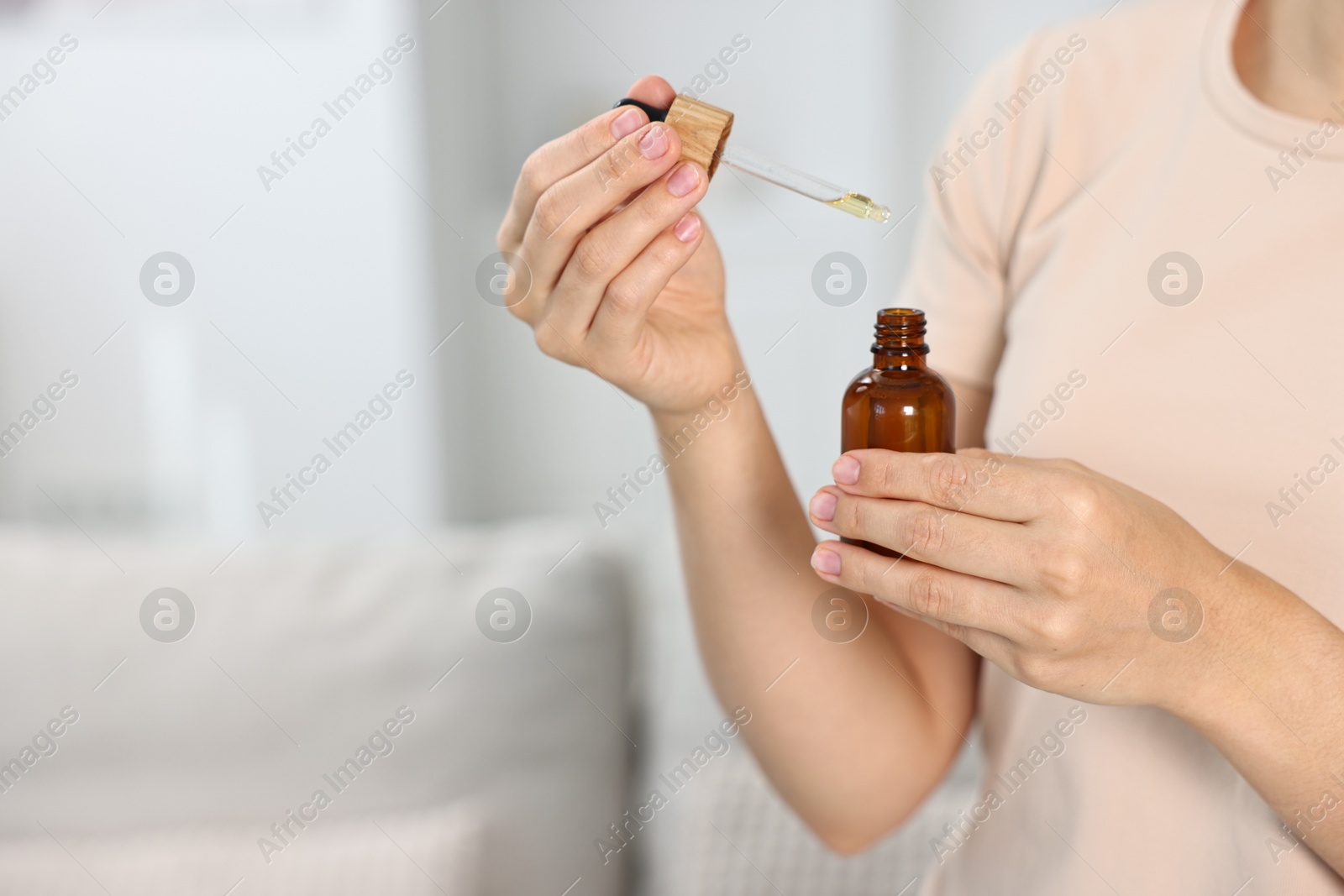 Photo of Young woman taking CBD tincture indoors, closeup. Space for text