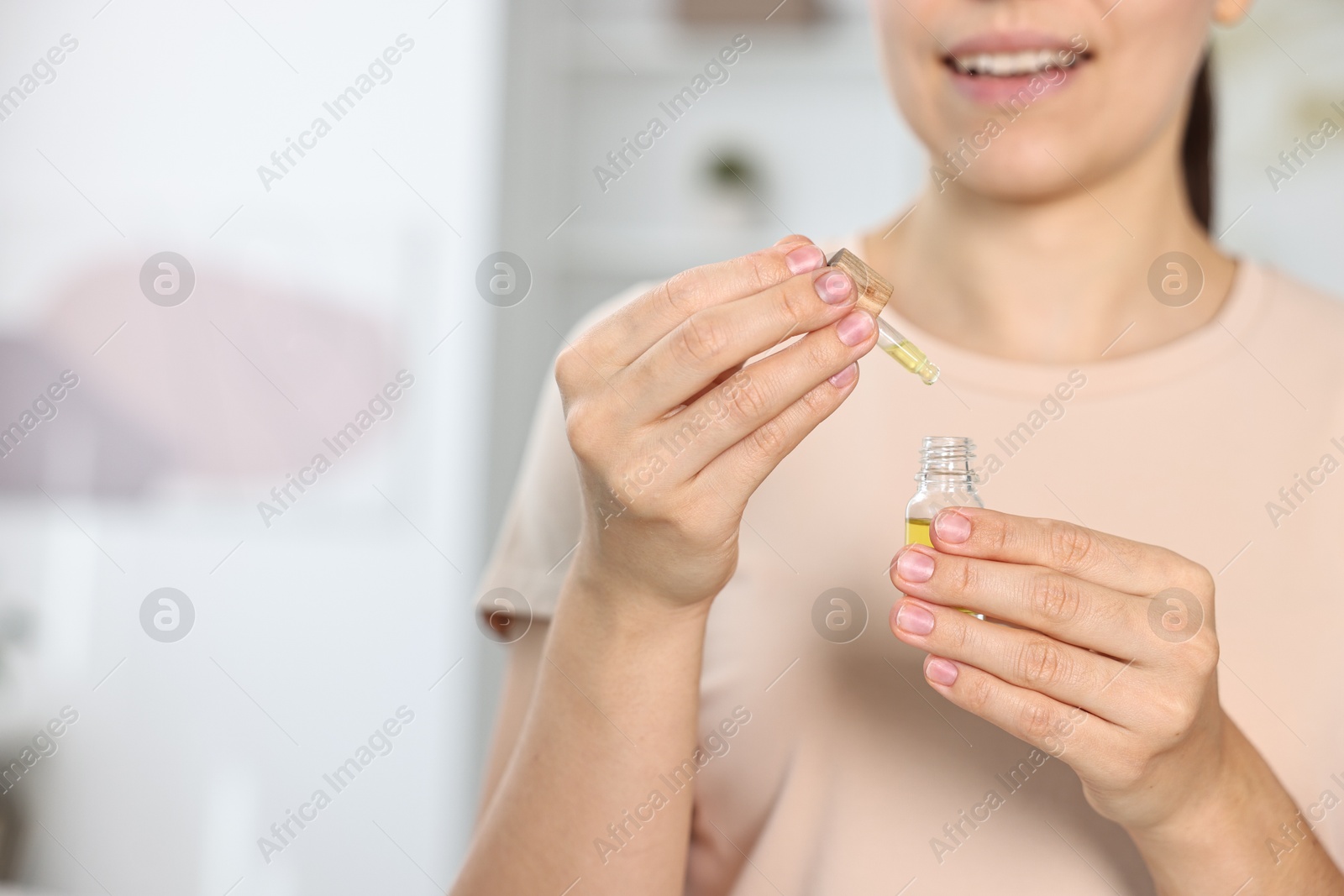 Photo of Young woman taking CBD tincture indoors, closeup. Space for text