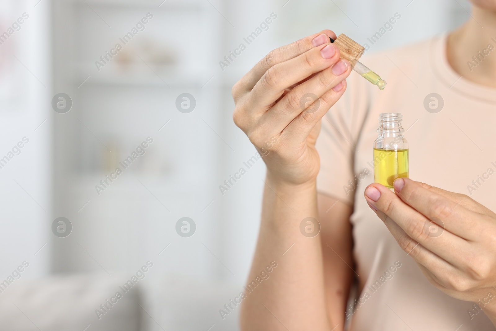 Photo of Young woman taking CBD tincture indoors, closeup. Space for text