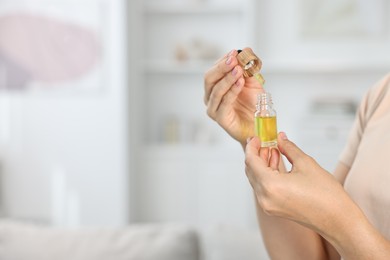 Young woman taking CBD tincture indoors, closeup. Space for text