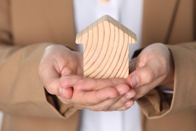 Photo of Property insurance. Real estate agent with wooden house figure, closeup