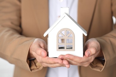 Photo of Property insurance. Real estate agent with house figure on light background, closeup