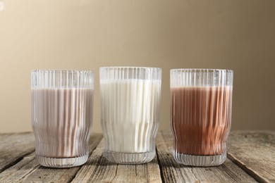 Photo of Different tasty protein cocktails in glasses on wooden table