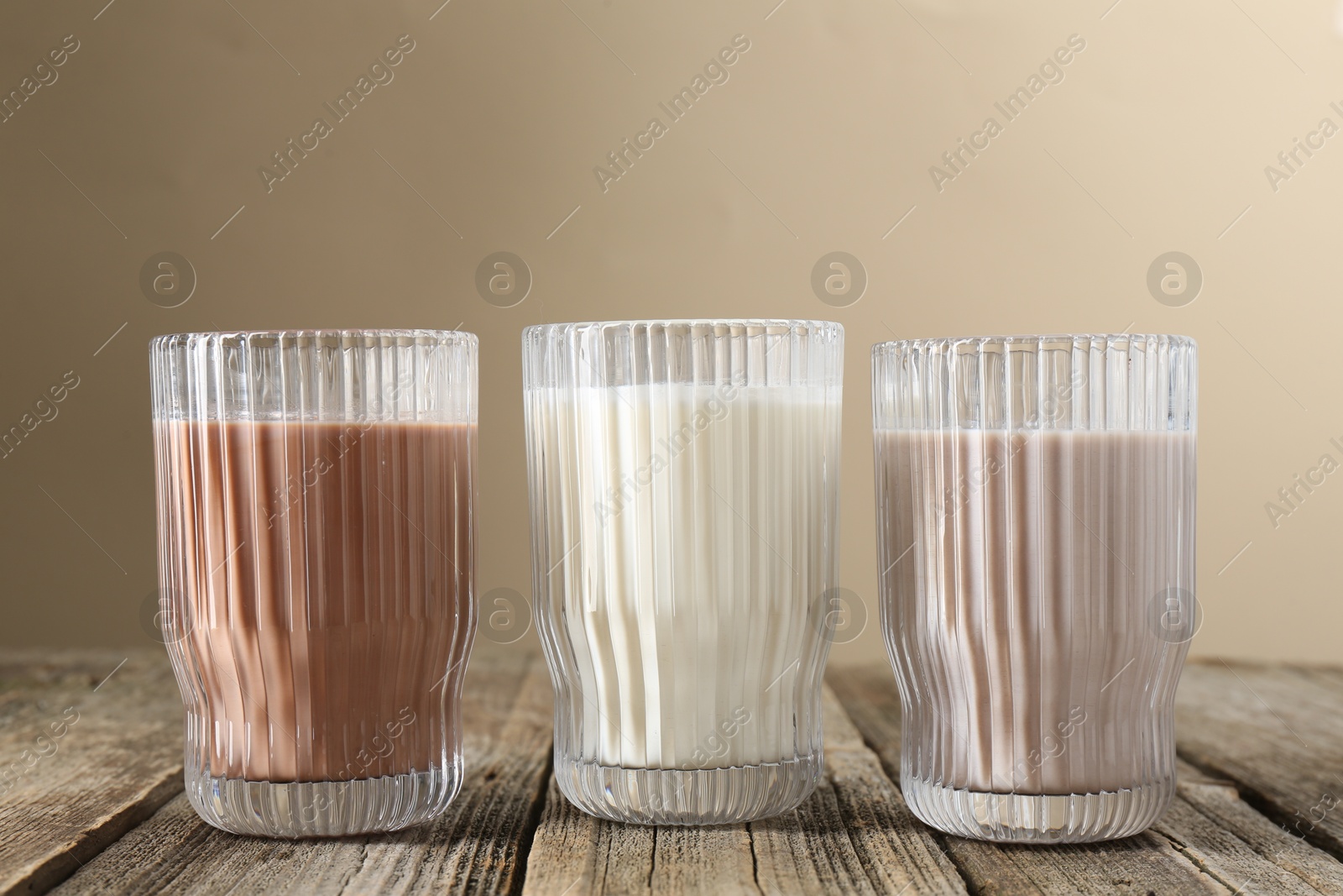 Photo of Different tasty protein cocktails in glasses on wooden table