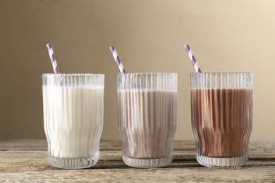 Photo of Different tasty protein cocktails in glasses on wooden table