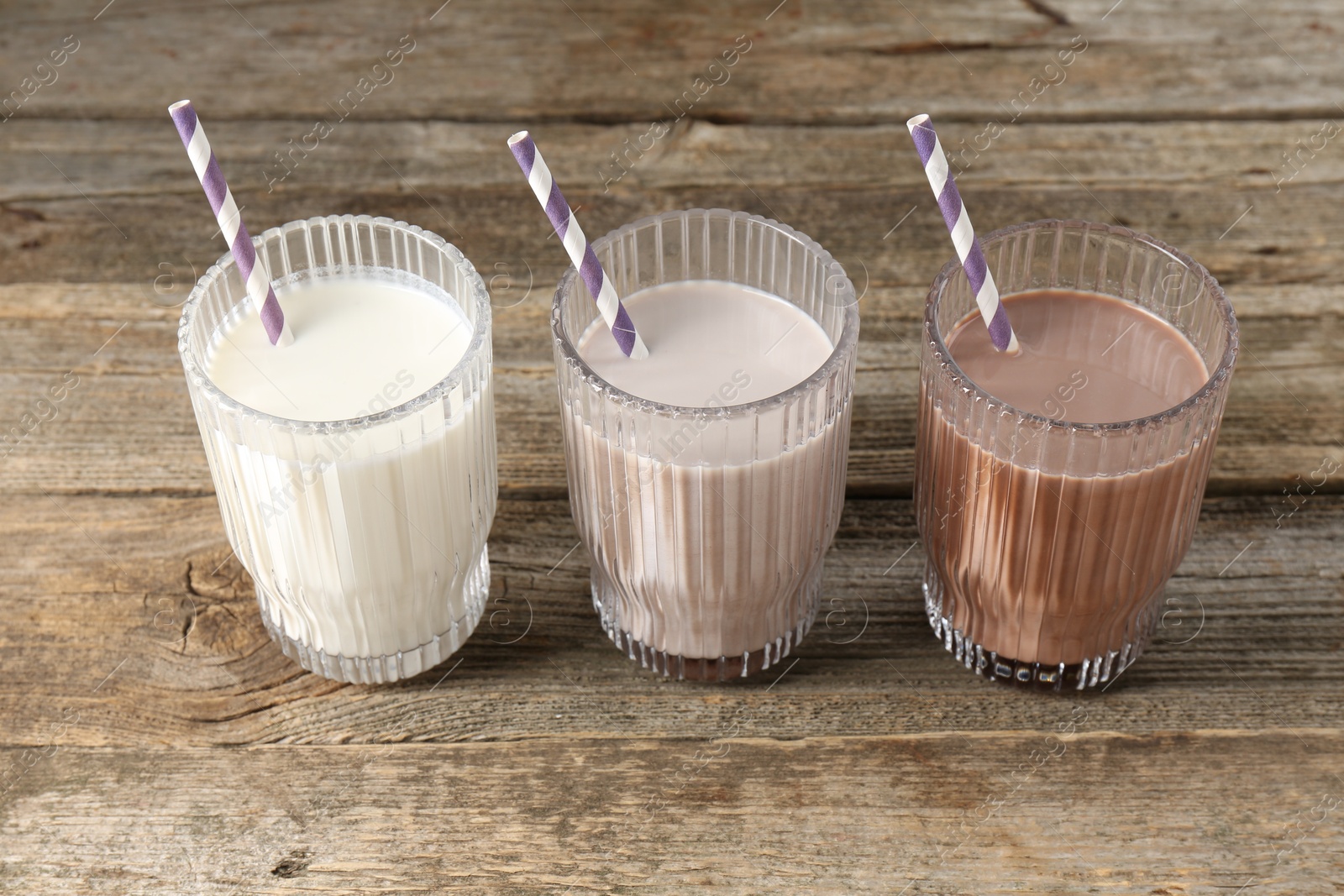 Photo of Different tasty protein cocktails in glasses on wooden table