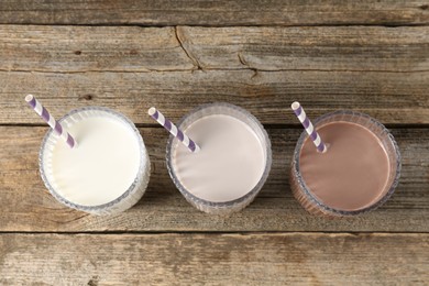 Photo of Different tasty protein cocktails in glasses on wooden table, above view