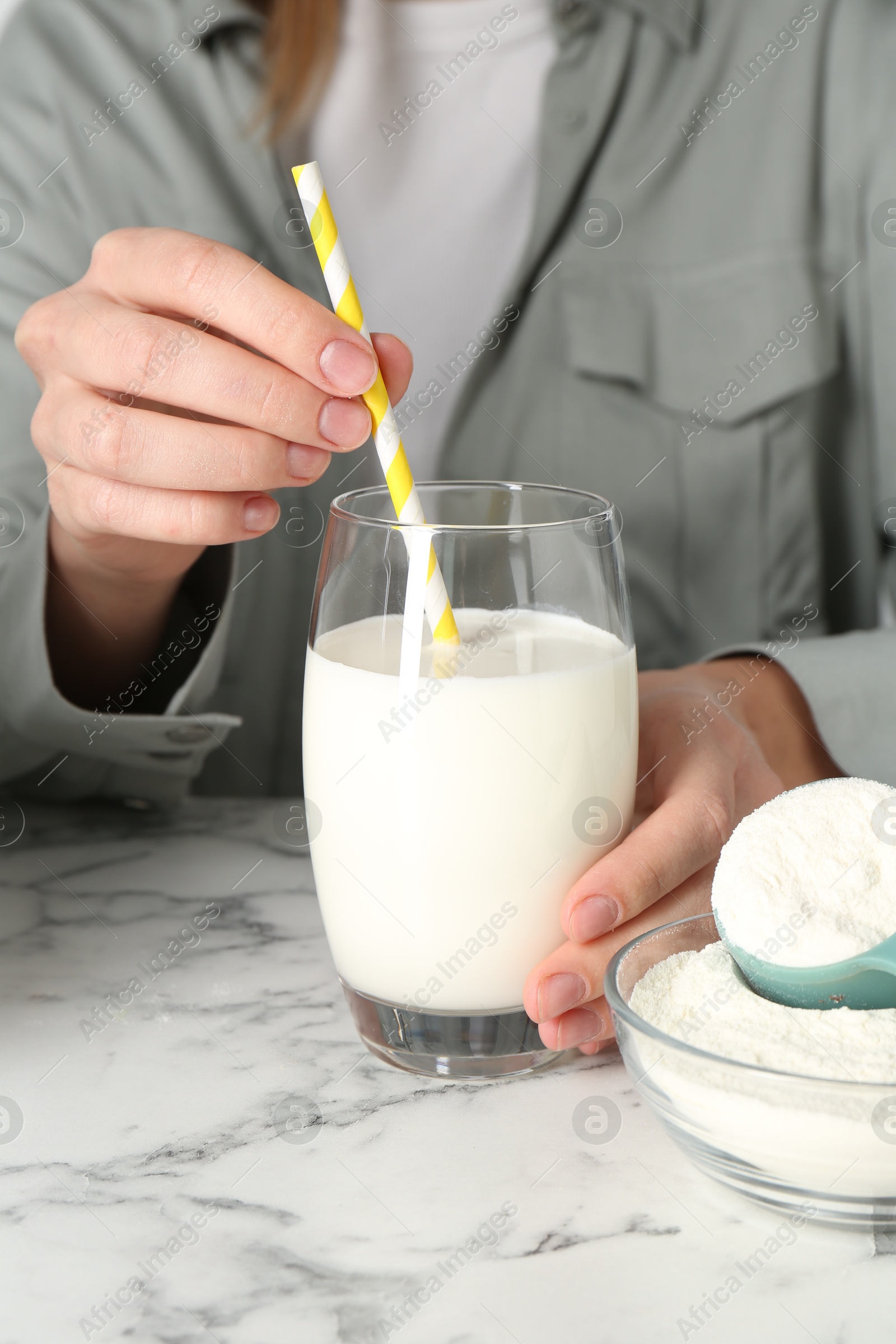 Photo of Woman with glass of protein cocktail at white marble table, closeup