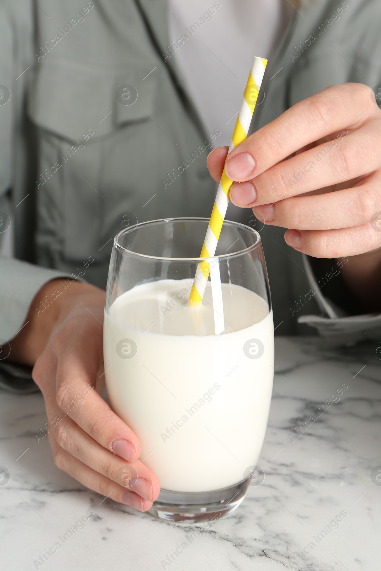 Photo of Woman with glass of protein cocktail at white marble table, closeup