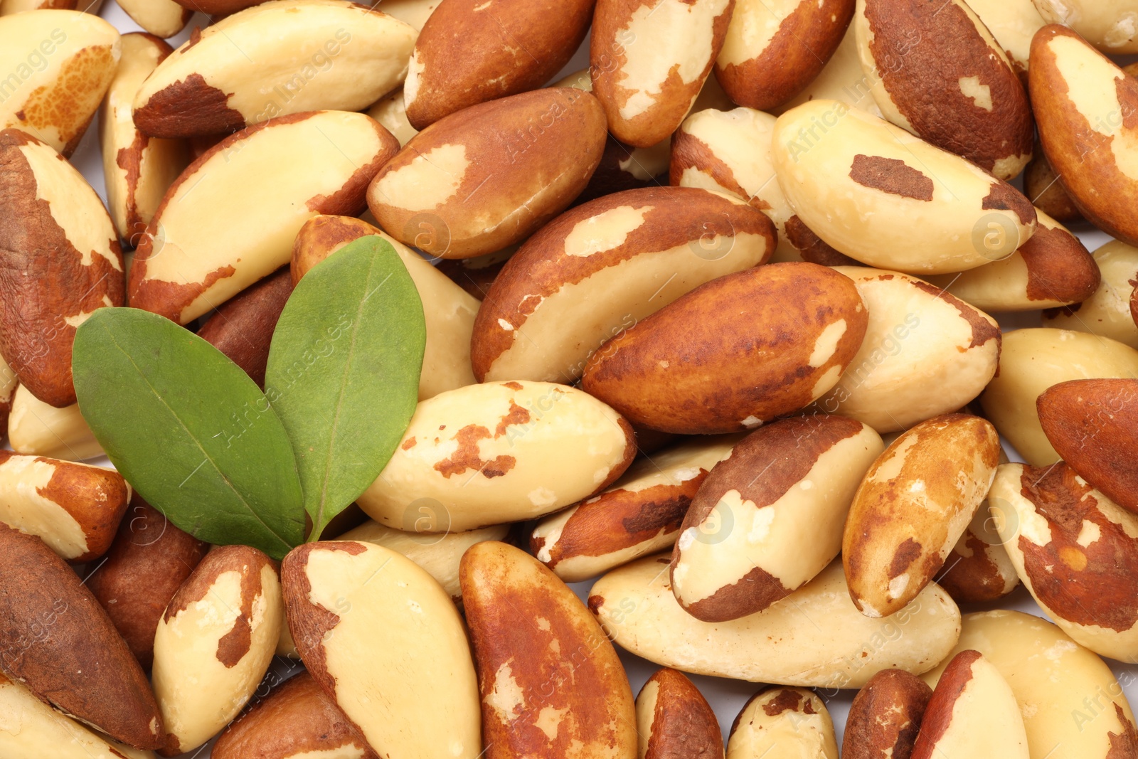 Photo of Tasty Brazil nuts and leaves as background, top view