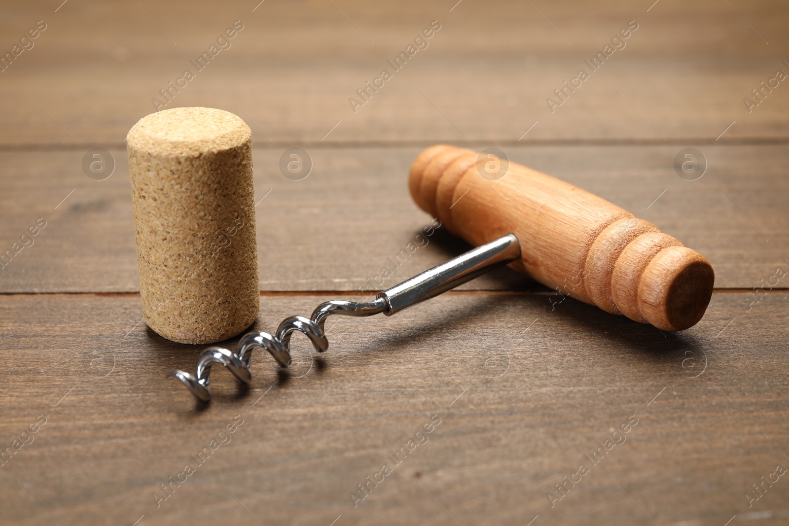 Photo of Corkscrew with handle and cork on wooden table