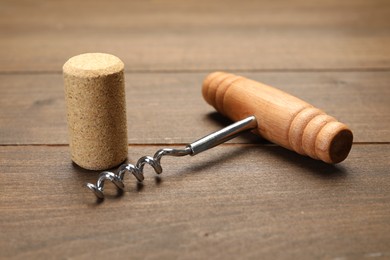 Corkscrew with handle and cork on wooden table