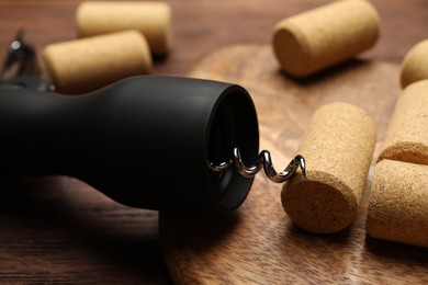 Wing corkscrew and corks on wooden table, closeup