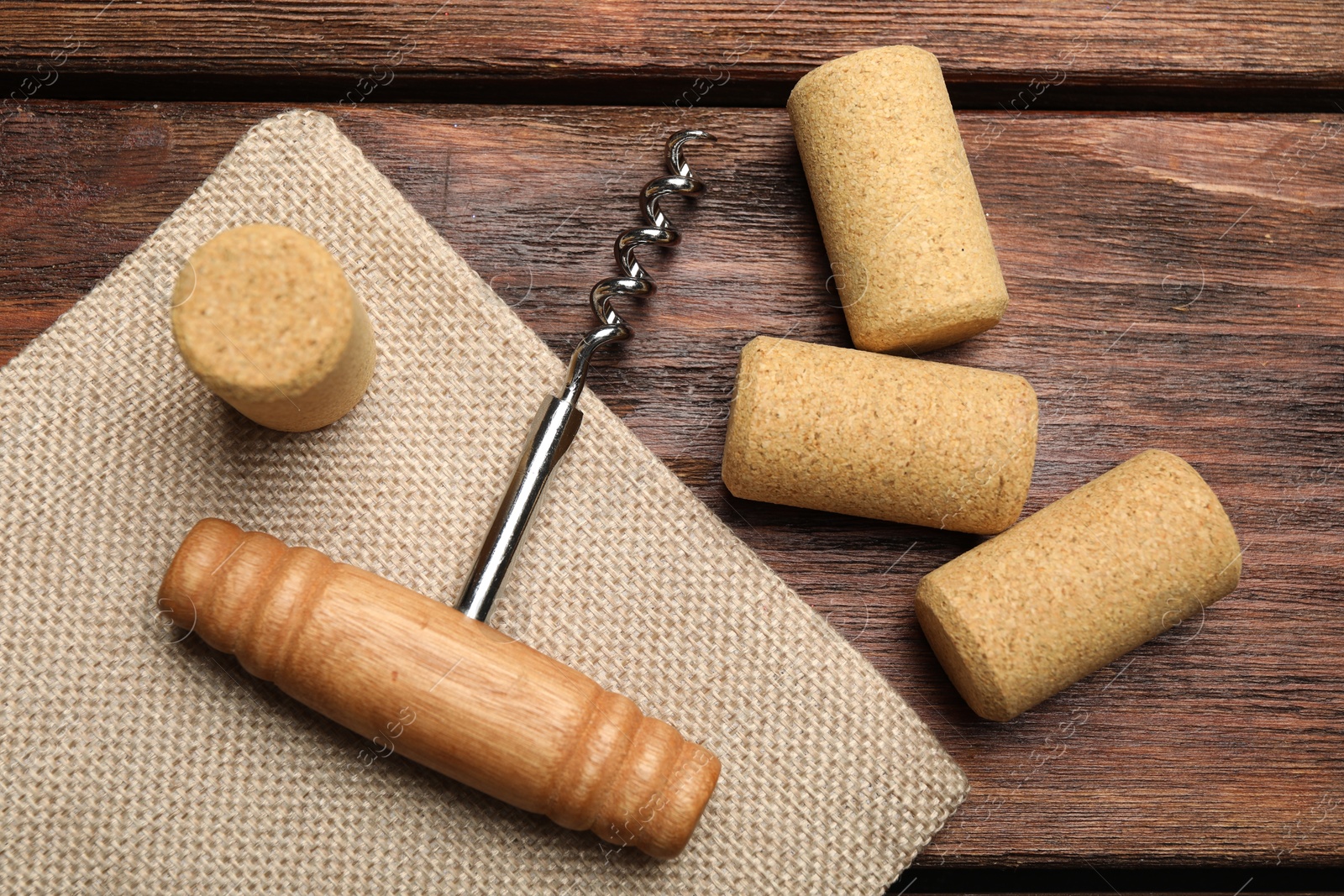 Photo of Corkscrew and corks on wooden table, flat lay