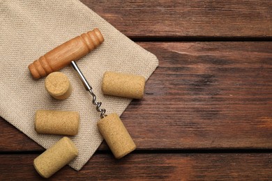 Corkscrew and corks on wooden table, flat lay. Space for text