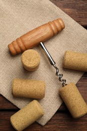 Photo of Corkscrew and corks on wooden table, flat lay