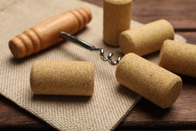 Photo of Corkscrew and corks on wooden table, closeup