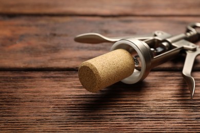 Photo of Wing corkscrew and cork on wooden table, closeup. Space for text