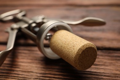 Photo of Wing corkscrew and cork on wooden table, closeup