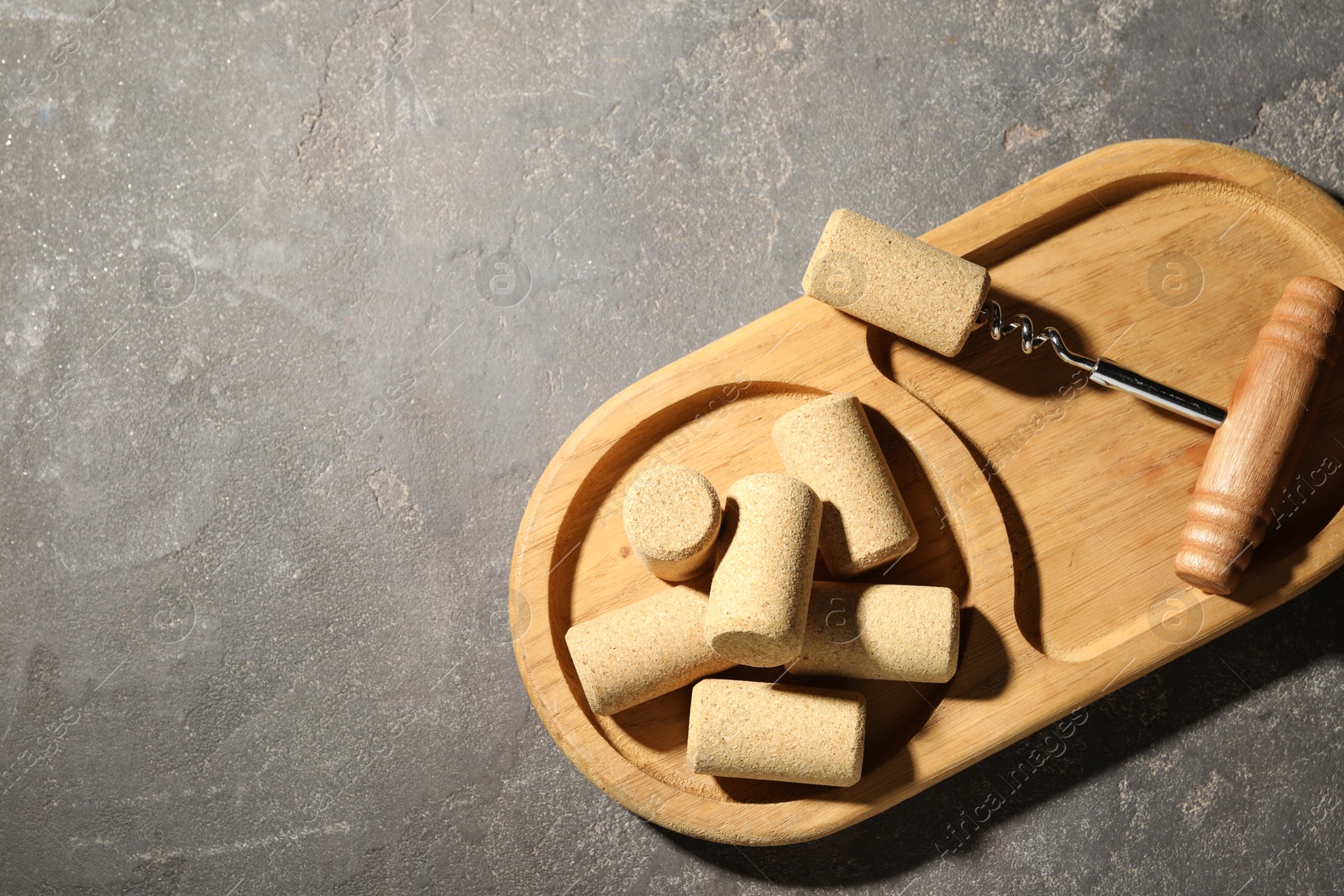 Photo of Corkscrew and corks on grey table, top view. Space for text