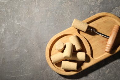 Corkscrew and corks on grey table, top view. Space for text