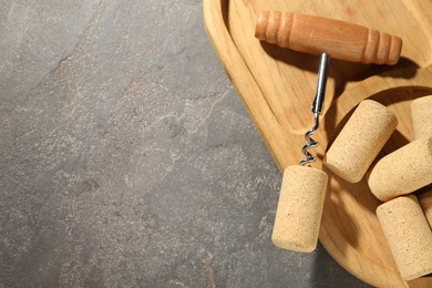 Corkscrew and corks on grey table, top view. Space for text