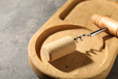 Corkscrew and cork on grey table, closeup