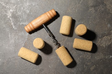 Corkscrew and corks on grey table, flat lay