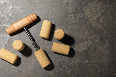 Corkscrew and corks on grey table, flat lay. Space for text