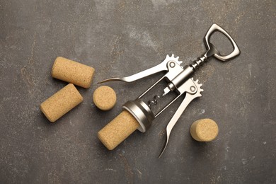 Photo of Wing corkscrew and corks on grey table, flat lay