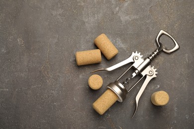 Wing corkscrew and corks on grey table, flat lay. Space for text