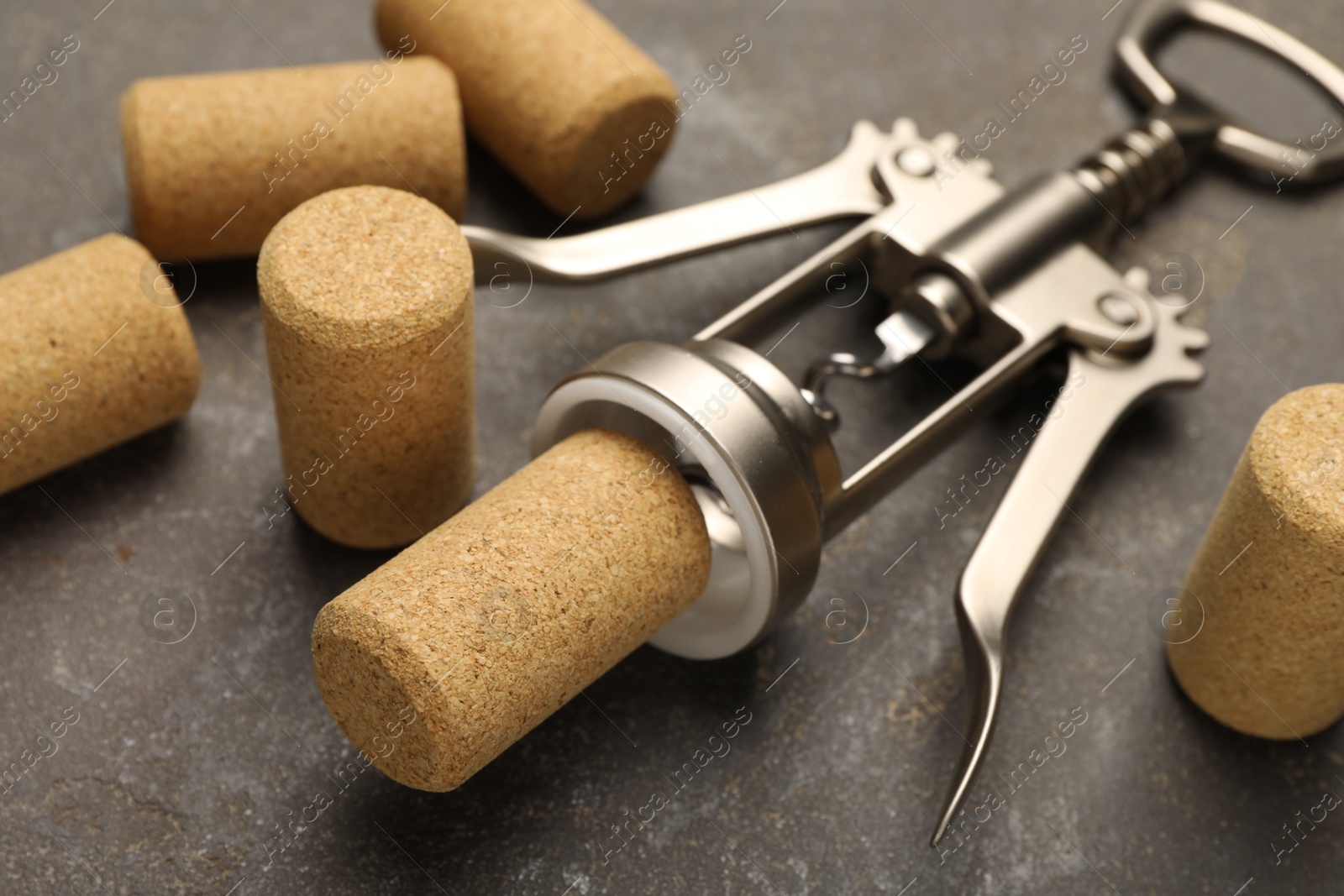 Photo of Wing corkscrew and corks on grey table, closeup