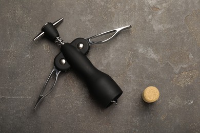 Wing corkscrew and cork on grey table, top view