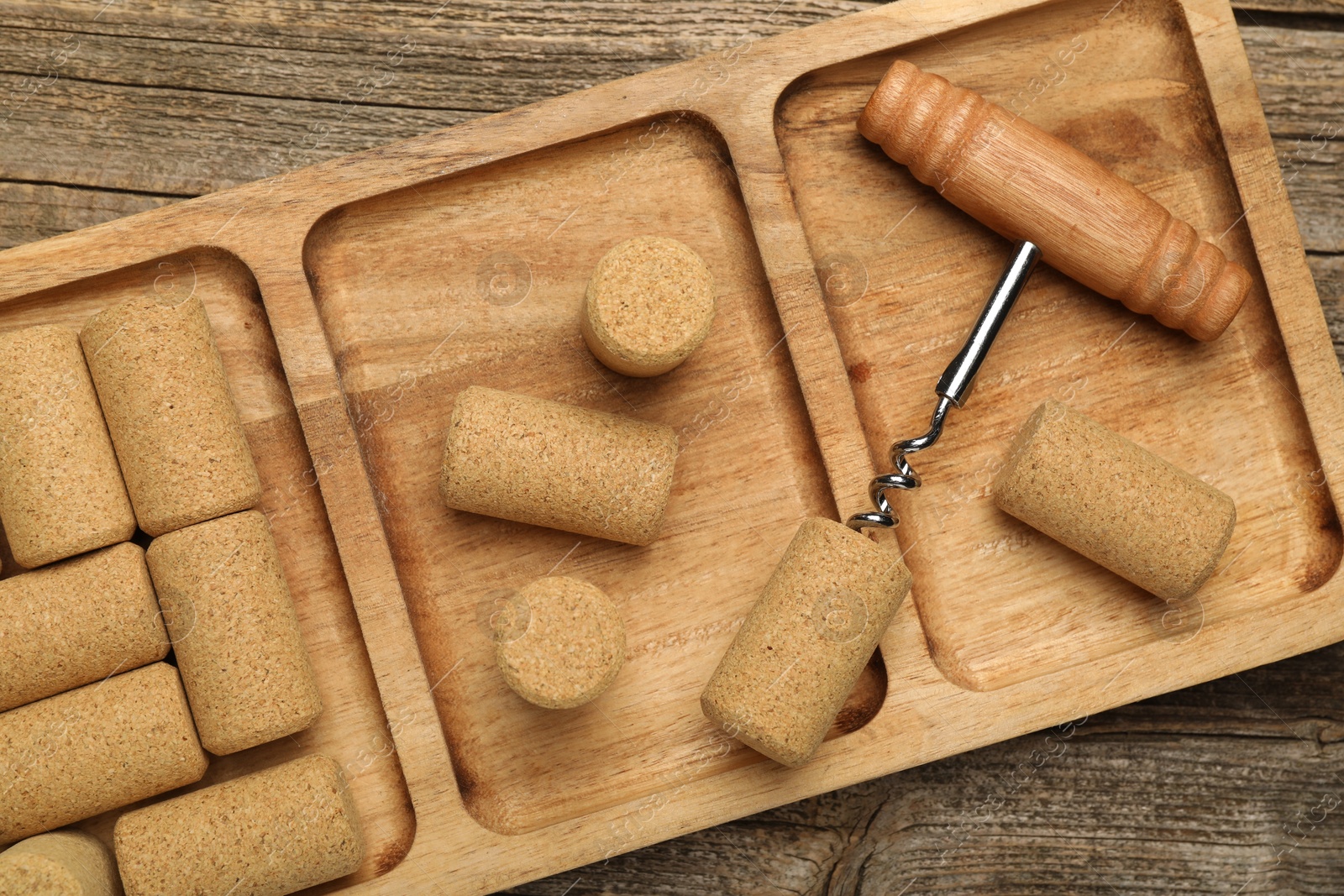 Photo of Corkscrew and corks on wooden table, top view