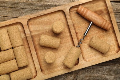 Corkscrew and corks on wooden table, top view