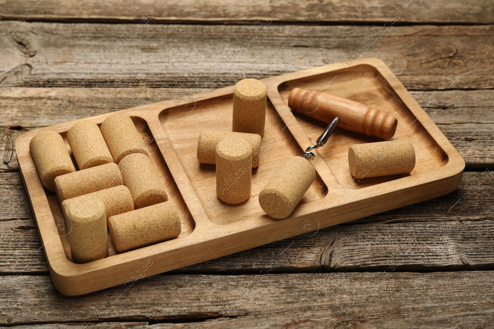 Photo of Corkscrew, tray and corks on wooden table