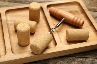 Photo of Corkscrew and corks on wooden table, closeup