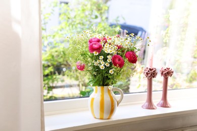 Photo of Beautiful ranunculus flowers and chamomiles in vase on windowsill indoors