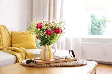 Photo of Beautiful ranunculus flowers and chamomiles in vase on table indoors, space for text