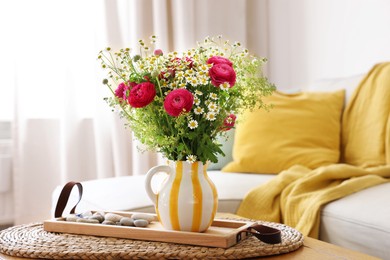 Beautiful ranunculus flowers and chamomiles in vase on table indoors