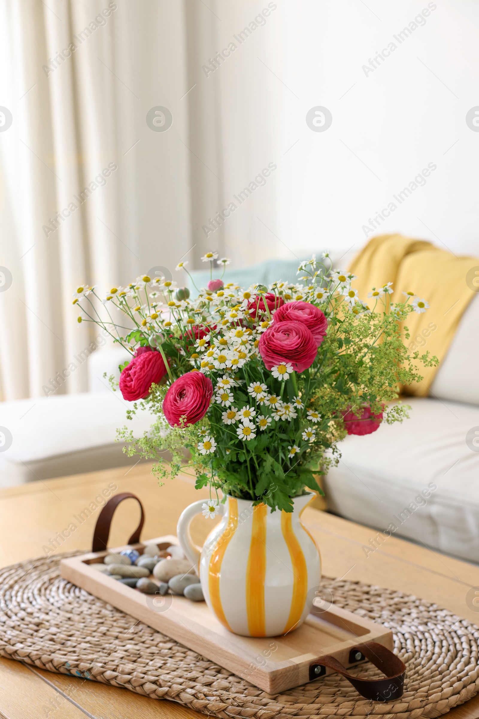 Photo of Beautiful ranunculus flowers and chamomiles in vase on table indoors