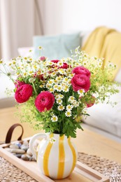 Photo of Beautiful ranunculus flowers and chamomiles in vase on table indoors